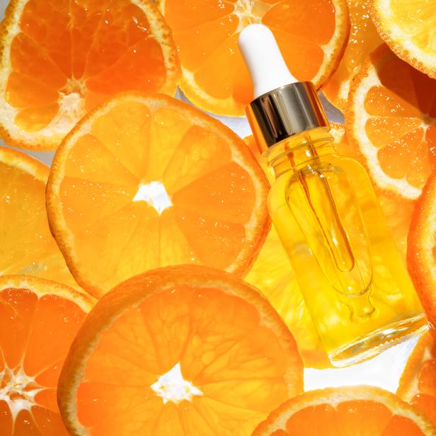 Eine Flasche mit Serum liegt auf einem Bett aus Orangenscheiben.