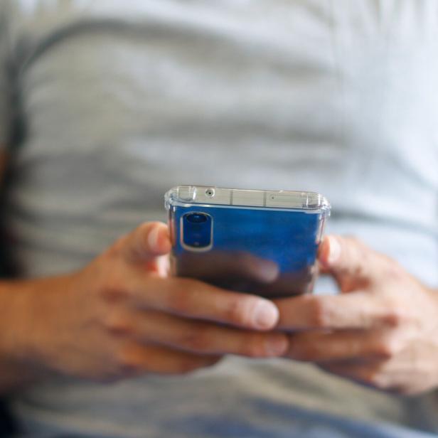 Ein Mann benutzt ein blaues Mobiltelefon.