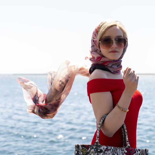 Eine Frau mit Sonnenbrille und Kopftuch vor dem Hintergrund des Meeres.