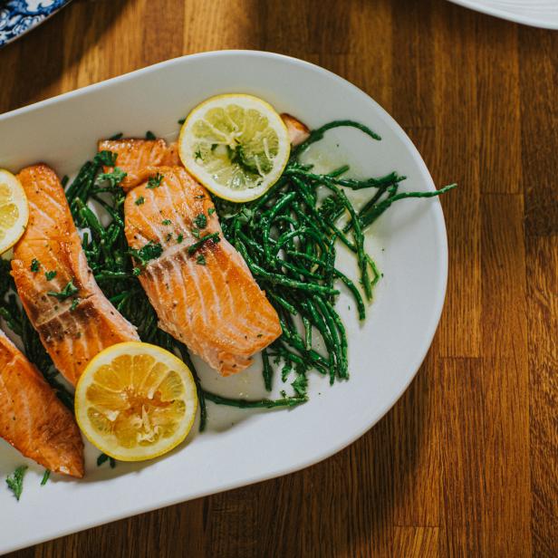 Gebratener Lachs mit Queller und Zitronenscheiben auf einem Teller.