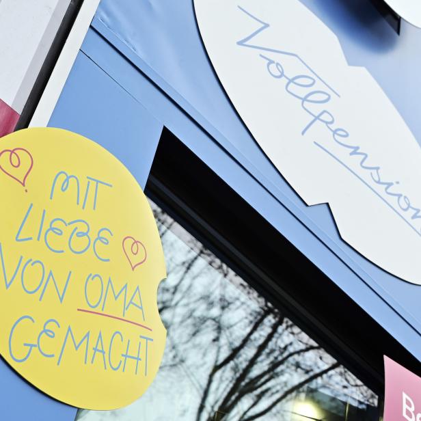 Ein Schild mit der Aufschrift „Mit Liebe von Oma gemacht“ und „Vollpension“ an einem Gebäude.