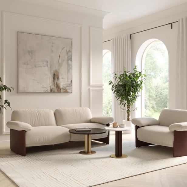 Ein Wohnzimmer mit einem Sofa, einem Sessel, zwei Tischen und Zimmerpflanzen.