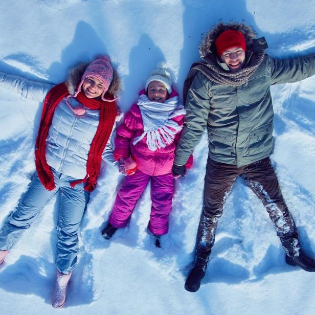 Eine Familie macht Schneeengel im Schnee.