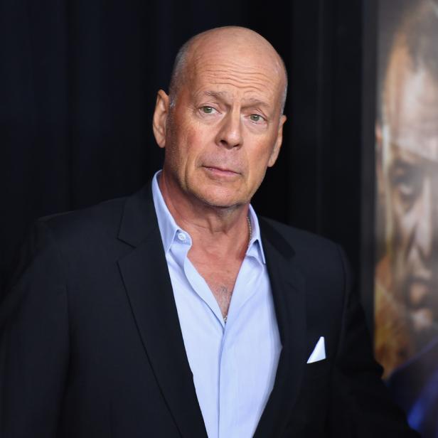 Bruce Willis posiert vor einem Filmplakat für den Film „Glass“.