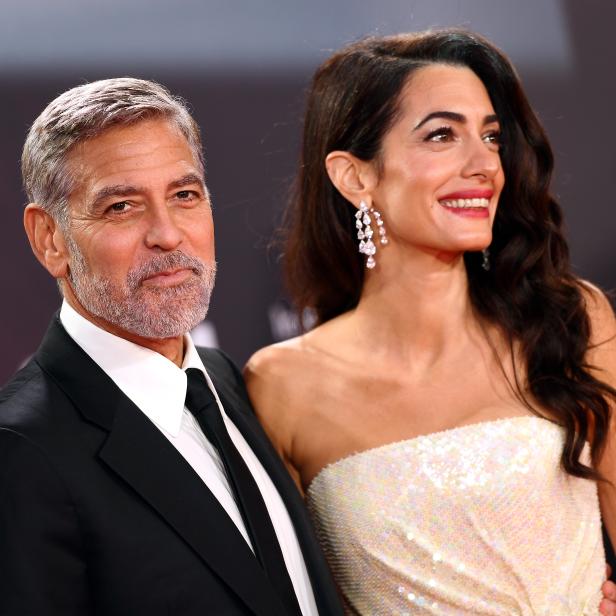 George und Amal Clooney posieren auf einem roten Teppich.