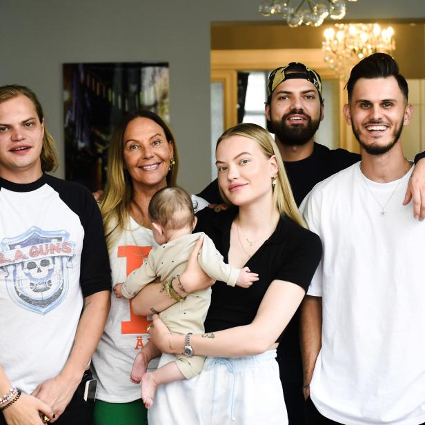 Eine Gruppe von sechs Personen, darunter eine Frau mit einem Baby im Arm, posiert für ein Foto.
