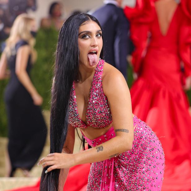 Lourdes Leon in einem pinkfarbenen, mit Schmucksteinen besetzten Kleid auf dem roten Teppich, die Zunge herausstreckend.