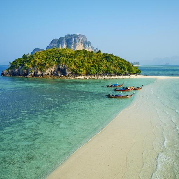 Ein tropisches Inselparadies mit türkisfarbenem Wasser und traditionellen thailändischen Booten.