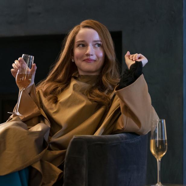 Julia Garner als Anna Delvey in der Netflix-Serie „Inventing Anna“ mit einem Champagnerglas in der Hand.