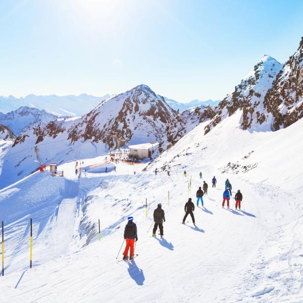Eine Gruppe von Skifahrern fährt eine schneebedeckte Piste in den Bergen hinunter.
