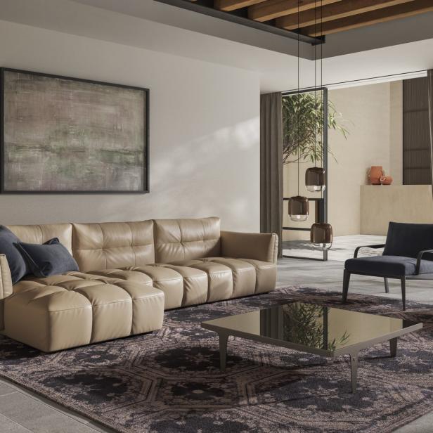 Ein Wohnzimmer mit einem beigen Ledersofa, zwei Sesseln und einem dunklen Teppich.