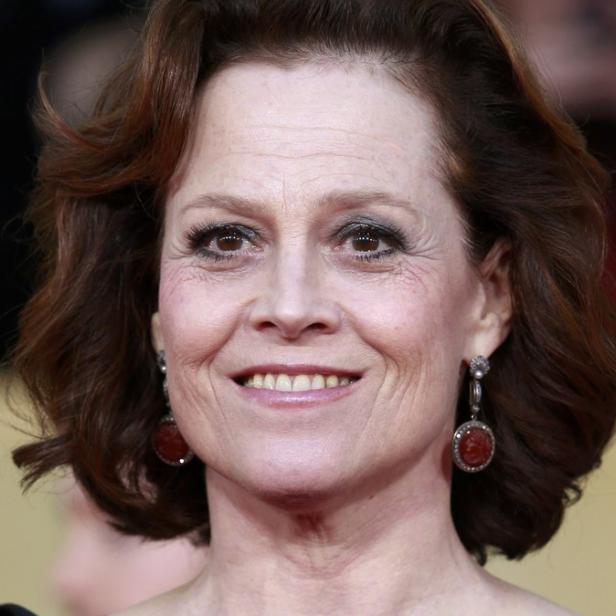 Porträt von Sigourney Weaver mit roten Ohrringen und lockigem Haar.