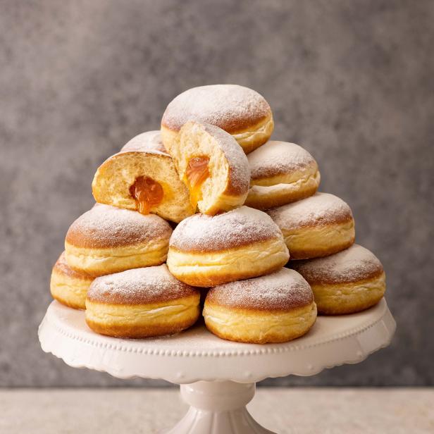 Ein Stapel Berliner Pfannkuchen mit Puderzucker auf einer weißen Etagere.