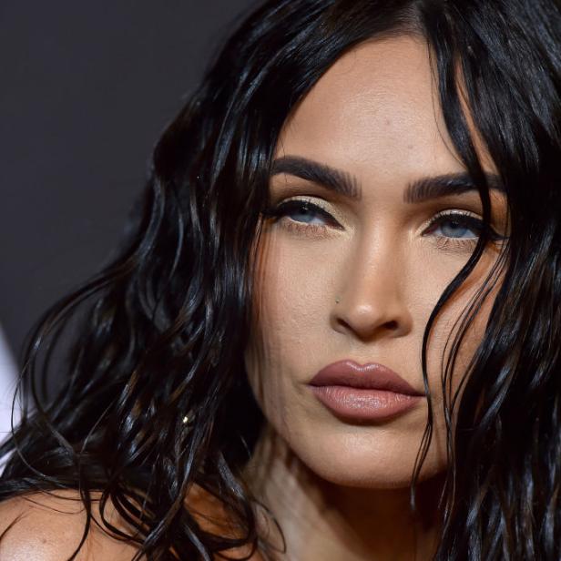 Nahaufnahme von Megan Fox mit gewelltem, dunklem Haar und hellem Make-up.
