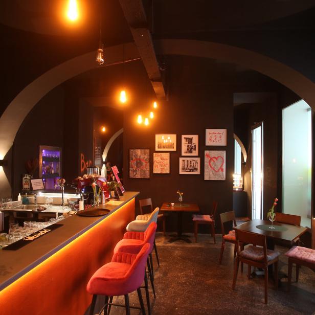 Innenansicht einer Bar mit dunkler Einrichtung und beleuchteter Theke.