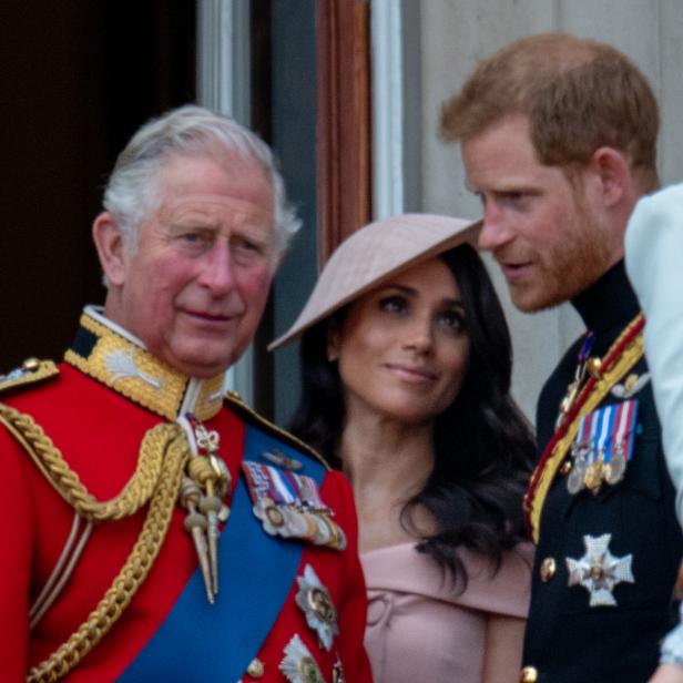 König Charles, Meghan Markle und Prinz Harry auf einem Balkon.