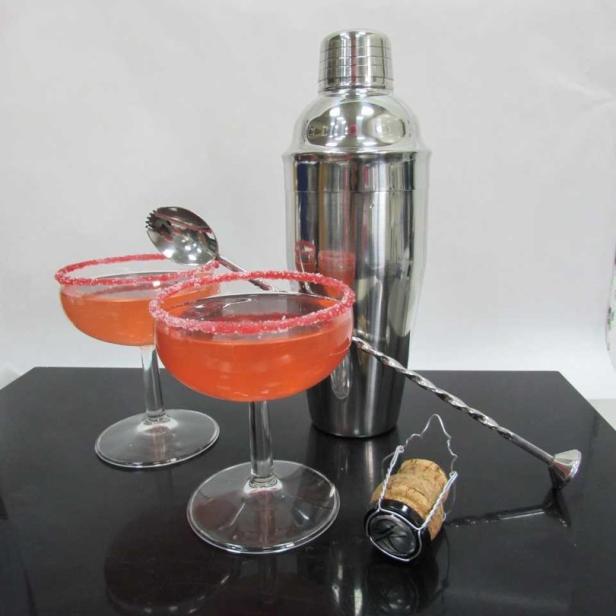 Zwei Cocktails mit Zucker am Glasrand und ein Cocktailshaker auf einem Tisch.