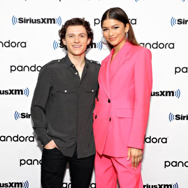 Tom Holland und Zendaya posieren vor einer Wand mit Logos von Pandora und SiriusXM.