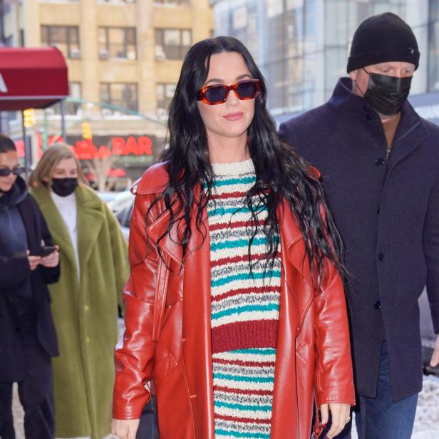 Katy Perry trägt einen roten Ledermantel und eine gestreifte Strickjacke.