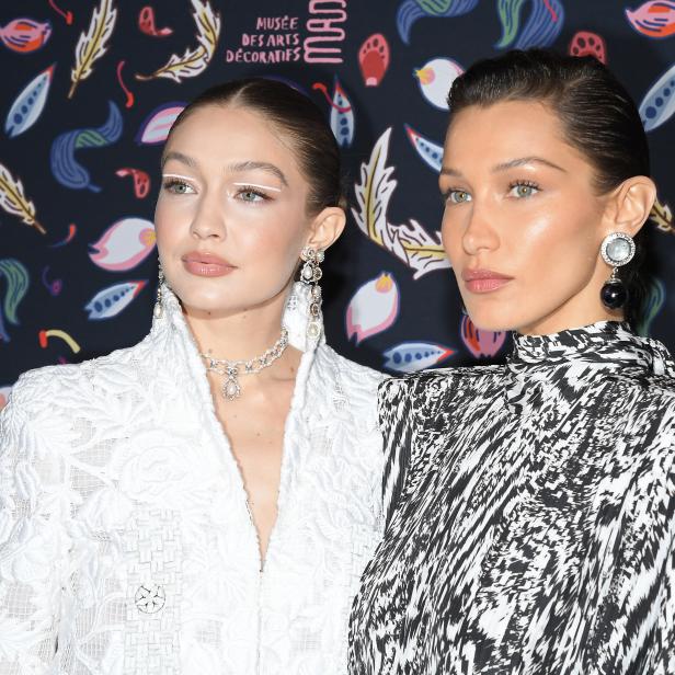 Gigi und Bella Hadid posieren vor einem farbenfrohen Hintergrund.