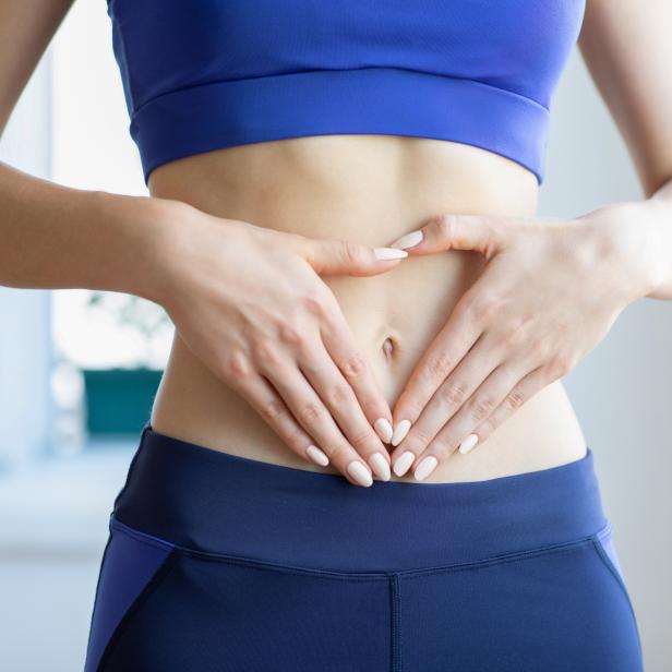 Eine Frau formt mit ihren Händen ein Herz auf ihrem Bauch.