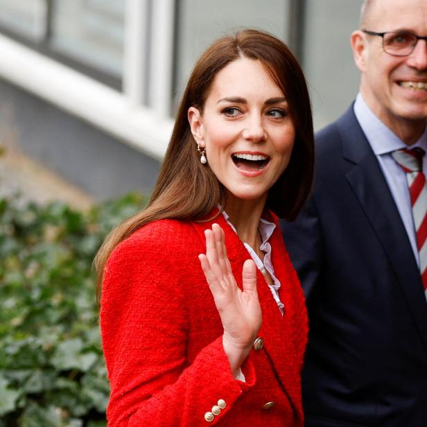Catherine, Princess of Wales, winkt in einer roten Jacke lächelnd in die Kamera.