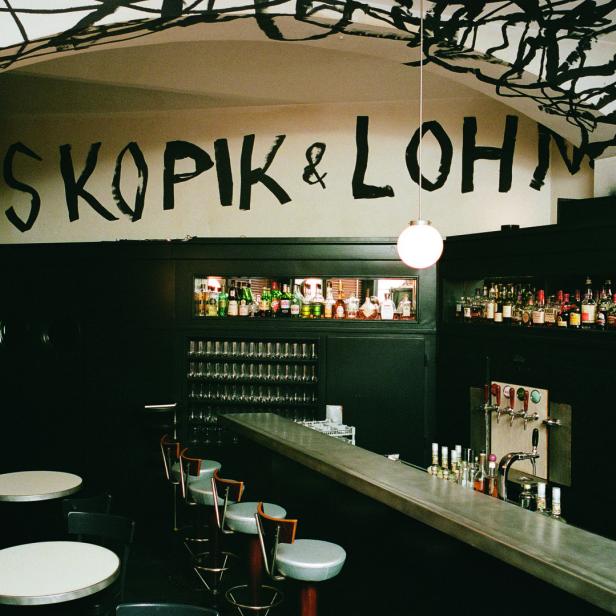 Innenansicht der Bar Skopic & Lohn mit dunkler Einrichtung und dem Schriftzug an der Wand.