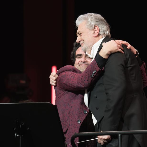 Plácido Domingo umarmt einen Dirigenten auf der Bühne.
