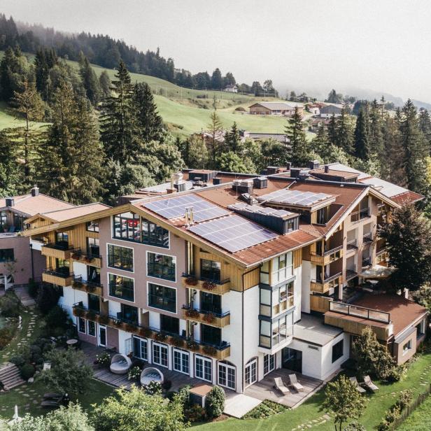 Ein großes Hotel mit Solaranlagen auf dem Dach inmitten einer grünen Landschaft.