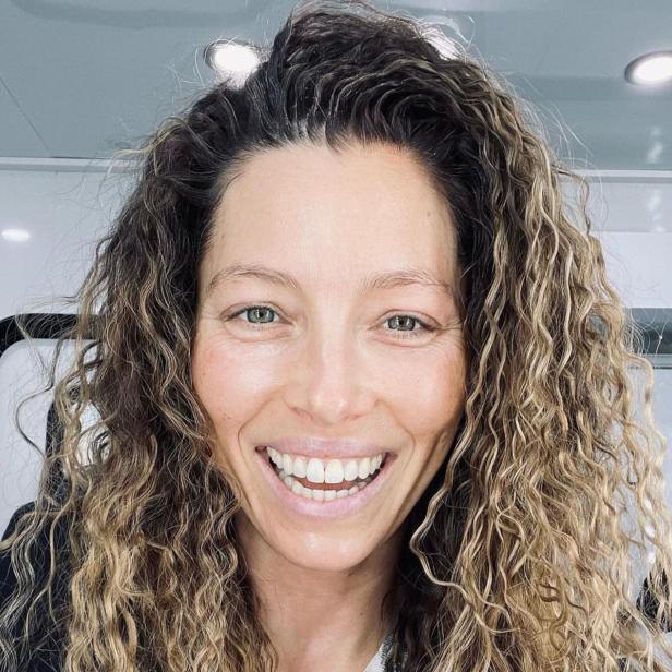 Ein Porträt von Jessica Biel mit lockigem Haar und einem strahlenden Lächeln.