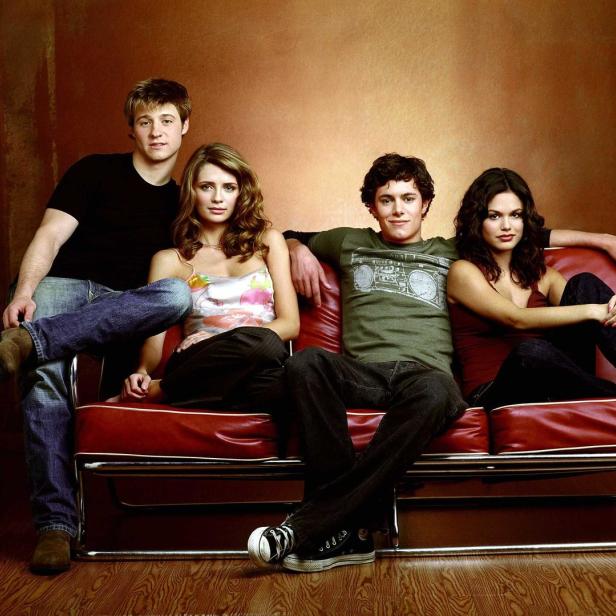 Die Schauspieler Adam Brody, Mischa Barton, Ben McKenzie und Rachel Bilson sitzen auf einer roten Couch.
