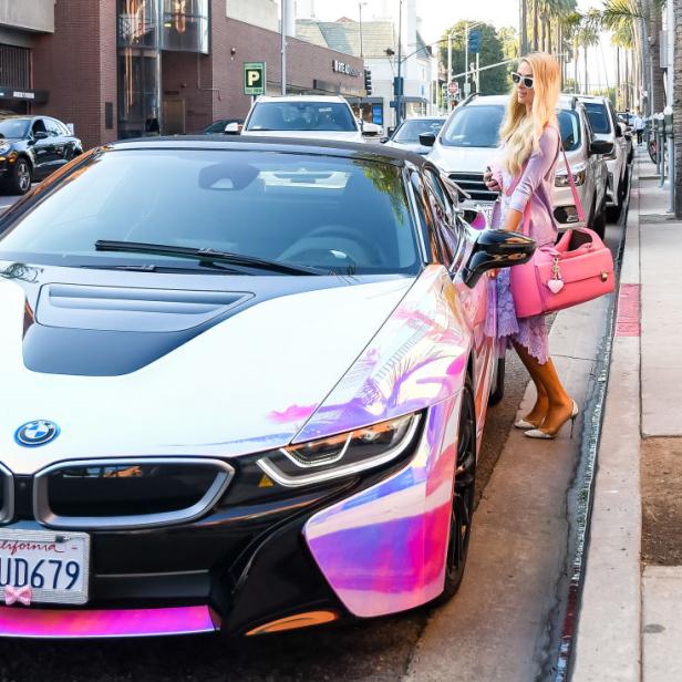 Paris Hilton steht neben ihrem auffälligen, farbwechselnden BMW i8.