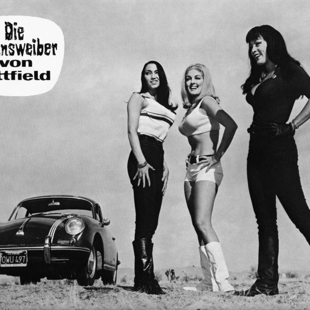 Drei Frauen posieren vor einem Porsche 356, im Hintergrund das Filmposter „Die Satansweiber von Tittfield“.