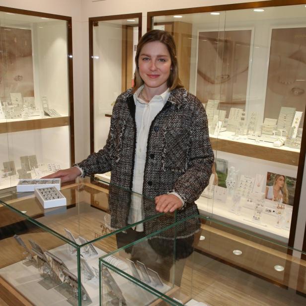 Eine Frau steht in einem Schmuckgeschäft hinter einer Vitrine.