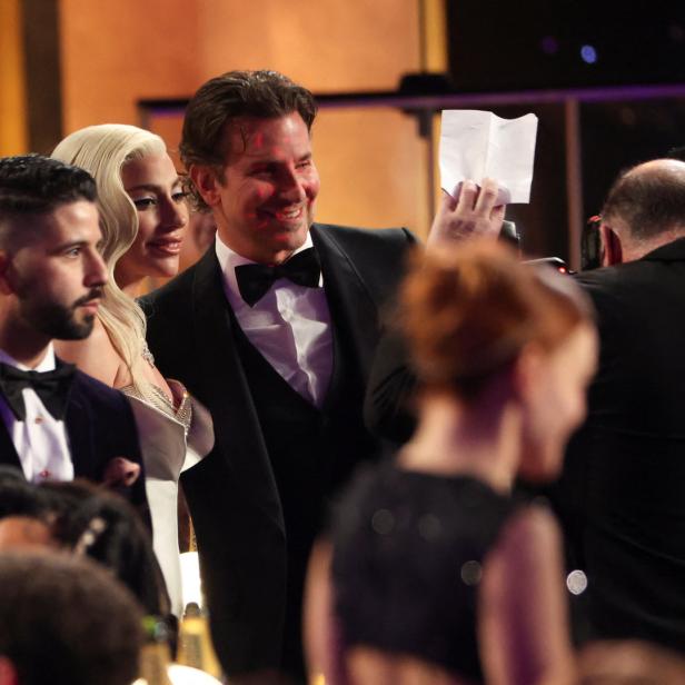 Bradley Cooper hält eine Notiz in der Hand, neben ihm Lady Gaga.
