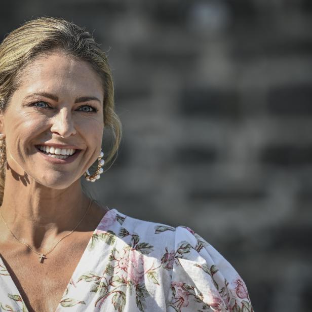 Prinzessin Madeleine lächelt in einem geblümten Kleid und Ohrringen in die Kamera.