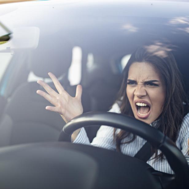 Eine wütende Frau gestikuliert und schreit im Auto.