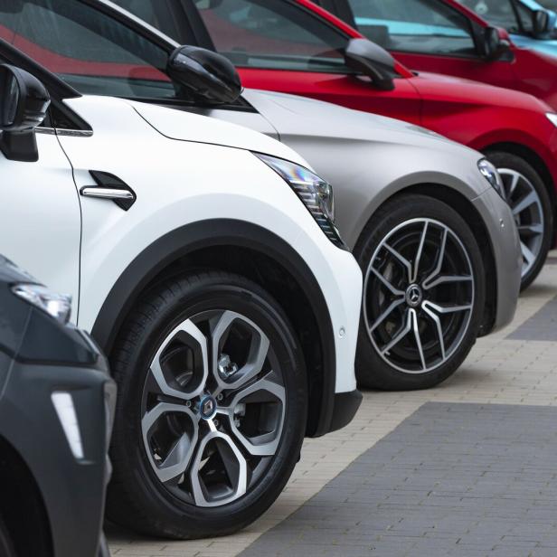 Mehrere Autos unterschiedlicher Farben stehen in einer Reihe geparkt.