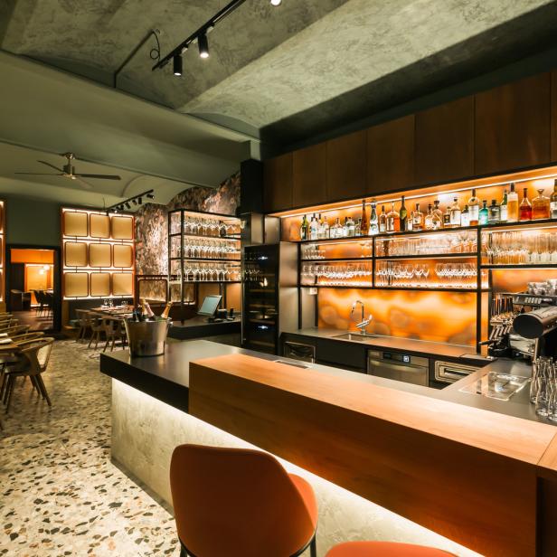 Innenansicht eines eleganten Restaurants mit Bar und gedeckten Tischen.