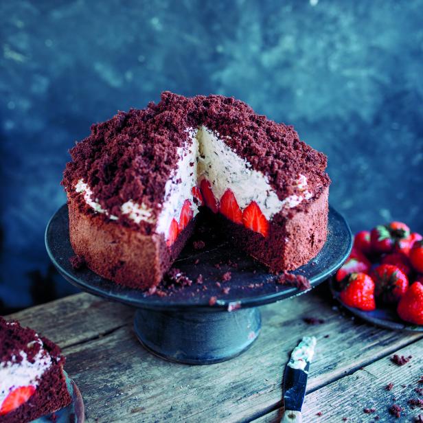 Ein angeschnittener Maulwurfkuchen mit Erdbeeren und Sahne auf einem Kuchenständer.