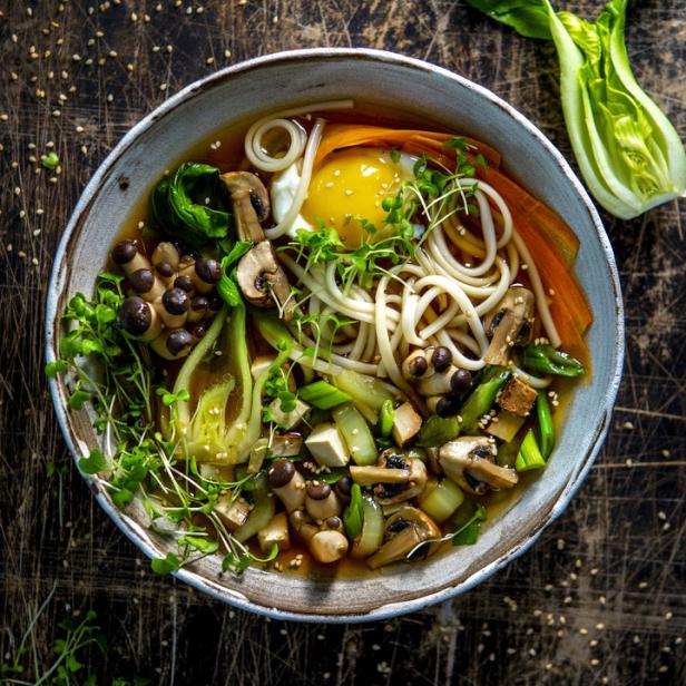 Eine Schüssel Udon-Nudelsuppe mit Pilzen, Tofu, Gemüse und einem pochierten Ei.