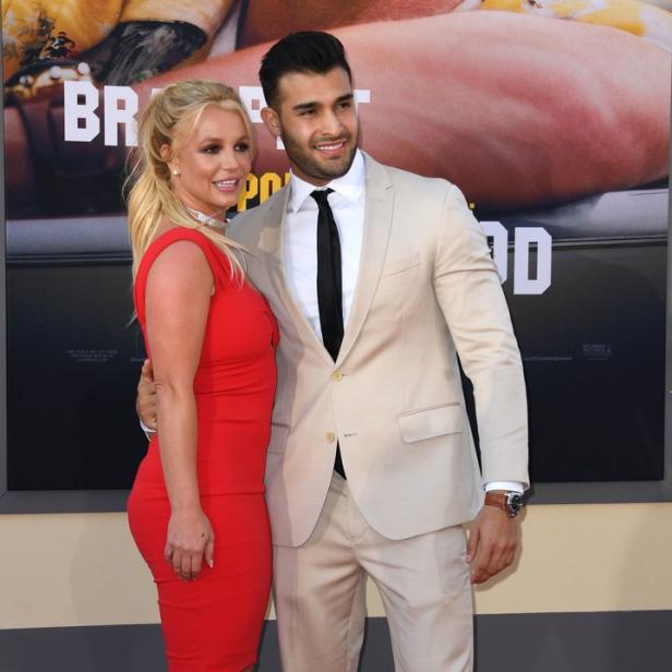 Britney Spears und Sam Asghari posieren auf dem roten Teppich vor einem Filmposter.