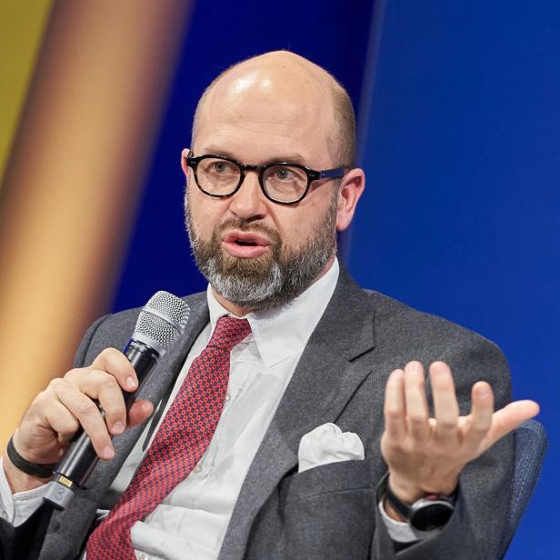 Ein Mann mit Brille und Bart spricht in ein Mikrofon.