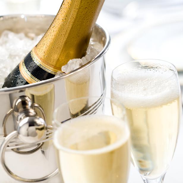 Eine Flasche Champagner in einem Eiskübel neben zwei gefüllten Gläsern.