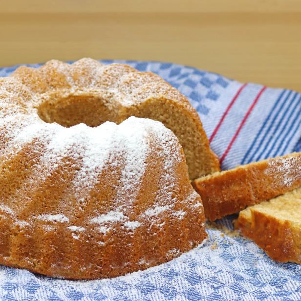 Ein Gugelhupf mit Puderzucker auf einem Küchentuch.