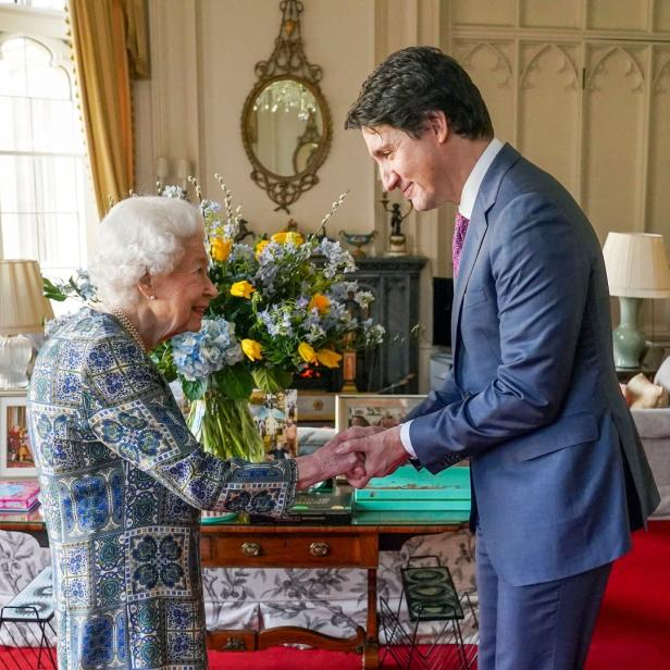 Königin Elizabeth II. schüttelt Justin Trudeau in einem Raum die Hand.