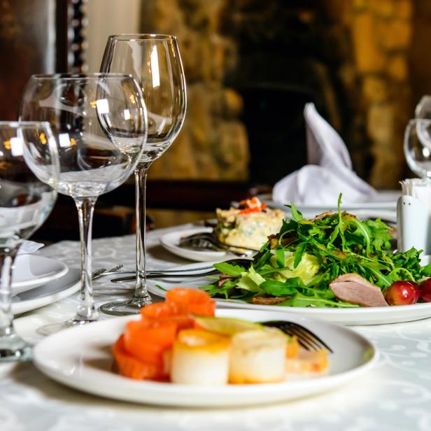 Ein gedeckter Tisch mit Salaten, Vorspeisen und Weingläsern in einem Restaurant.