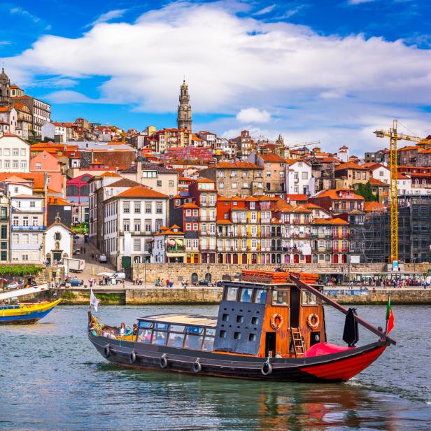 Blick auf die bunten Häuser von Porto, Portugal, mit traditionellen Booten auf dem Douro-Fluss.