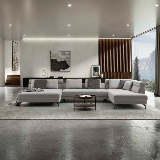 Ein großes, graues Ecksofa in einem modernen Wohnzimmer mit Blick auf einen See.