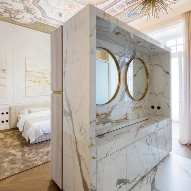 Ein Badezimmer mit Marmorwaschtisch und Spiegeln in einem luxuriösen Schlafzimmer.